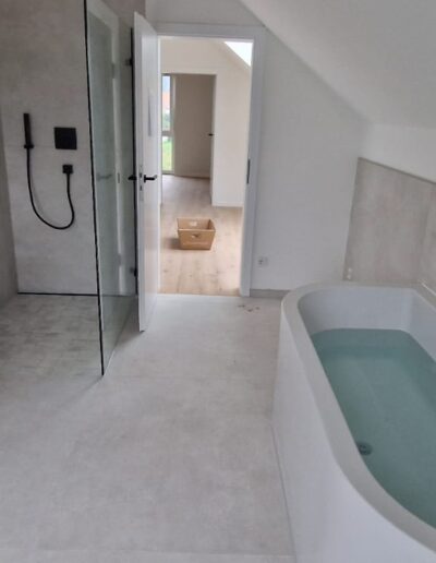 Modernes Badezimmer mit freistehender Badewanne, bodengleicher Dusche und schwarzen Armaturen nach Renovierung durch PC Trockenbau